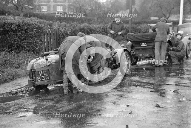 Attaching snow chains to JE Lancaster's Riley Brooklands during the Inter-Varsity Trial, 1930. Artist: Bill Brunell.