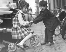 Children playing with a tricycle, c1960s.