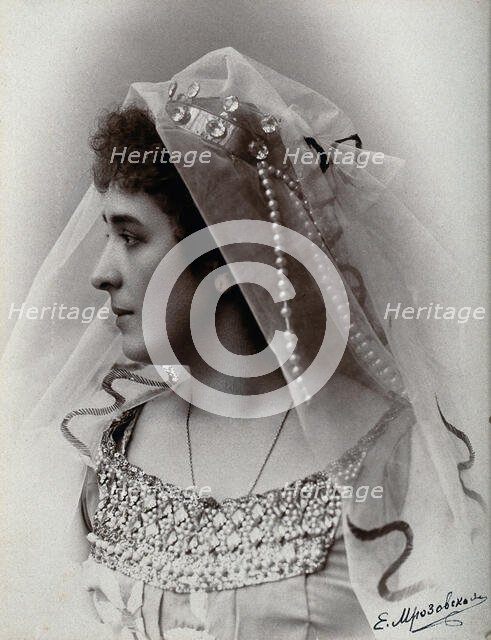 A woman posing in a photographic studio, wearing a bridal? dress and veil, in front of..., 1900-1910 Creator: Unknown.