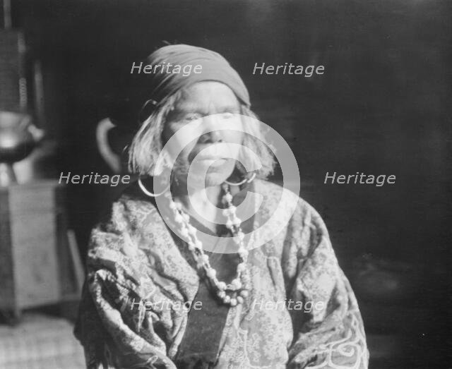 Ainu woman wearing a headscarf, earrings, and a necklace, 1908. Creator: Arnold Genthe.