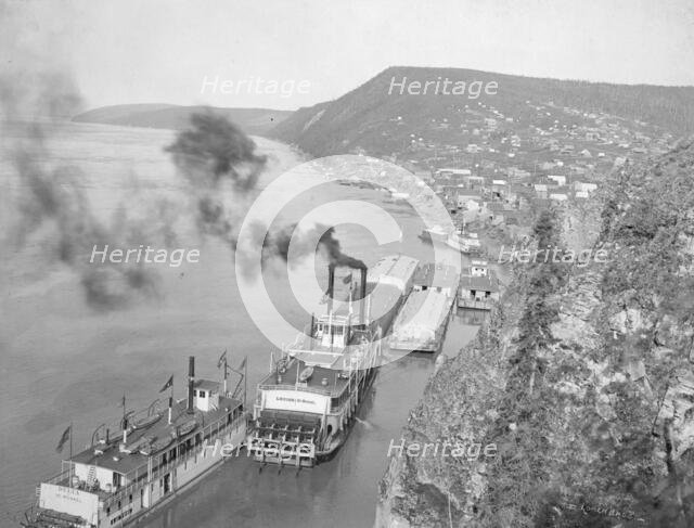 Riverboats distant view of town, between c1900 and 1923. Creator: Unknown.