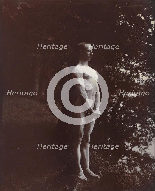 A man posing naked, standing with his chest out, arms down and hands clasped, approx 1900. Creator: Unknown.