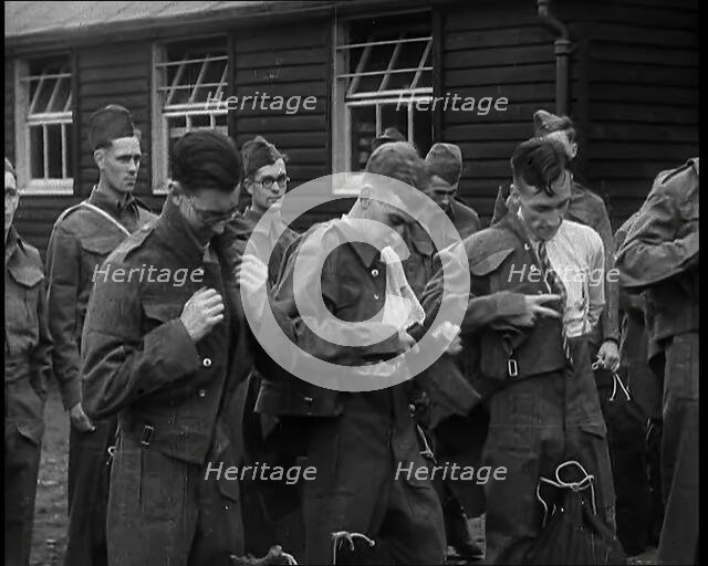 Male British Soldiers Putting on The Tunics of Their Uniforms in Front of Wooden Hut, 1939. Creator: British Pathe Ltd.