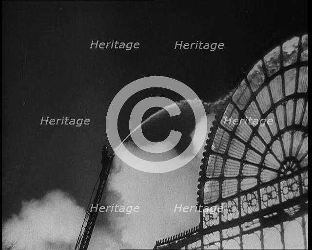 A Firefighter on a Ladder Trying to Extinguish the Crystal Palace Fire, 1936. Creator: British Pathe Ltd.