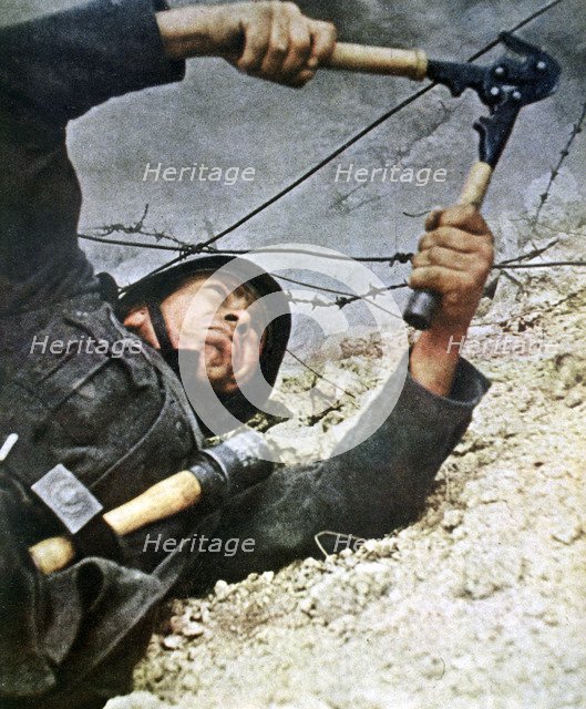 A German soldier cutting through barbed wire during an assalt, 1942. Artist: Unknown