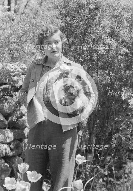 DeLamar, Alice, Miss, with dog, standing outdoors, between 1927 and 1942. Creator: Arnold Genthe.