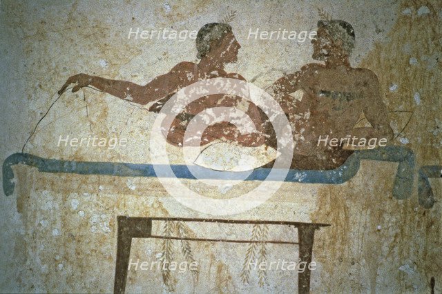 Fresco depicting two men lying on a bed in the Tuffatore tomb at Paestum.