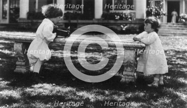 One child aiming camera, on bench, at another child, Washington, D.C., between c1890 and c1910. Creator: Frances Benjamin Johnston.
