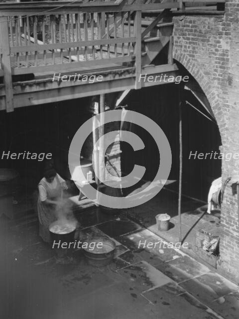 Woman doing laundry in a courtyard, New Orleans, between 1920 and 1926. Creator: Arnold Genthe.