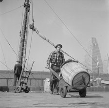 Dock stevedore at the Fulton fish market moving a barrel of codfish, New York, 1943. Creator: Gordon Parks.