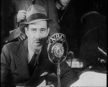 A Male American Civilian in a Press Room Speaking at a Microphone That Has the Words NBC..., 1930s. Creator: British Pathe Ltd.