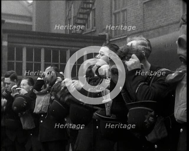 Male Police Civil Defence Volunteers Practice Putting on Gas Masks in a Yard Behind a Brick..., 1938 Creator: British Pathe Ltd.