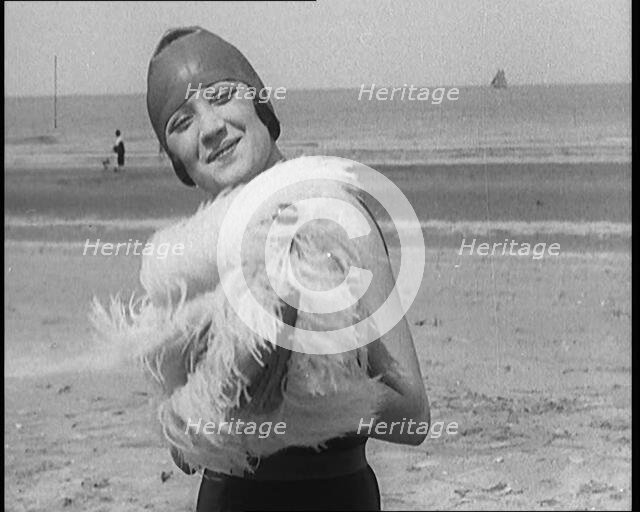 Female Civilian Wearing a Swimsuit Holding a Feathered Parasol at the Beach, 1920. Creator: British Pathe Ltd.