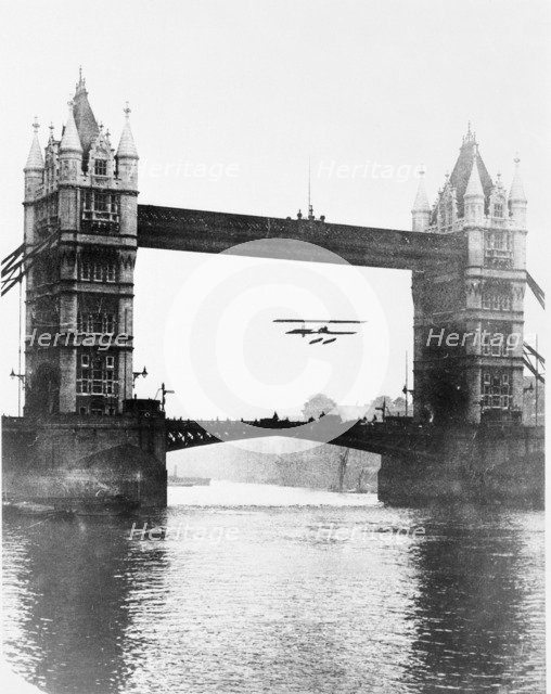Biplane flying under Tower Bridge, Stepney, Tower Hamlets, London. Artist: Unknown