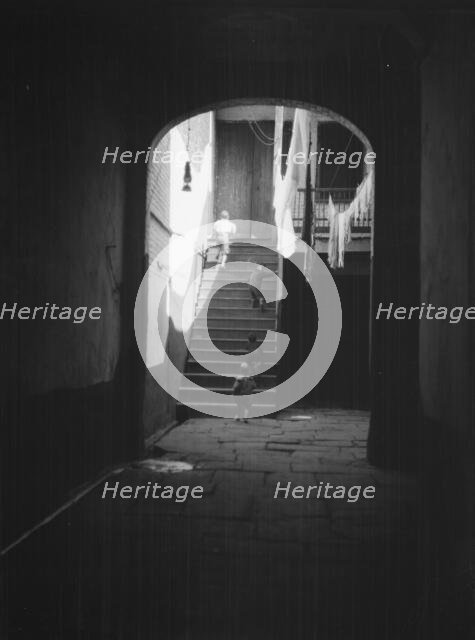 View of a courtyard through an arched passageway, New Orleans, between 1920 and 1926. Creator: Arnold Genthe.