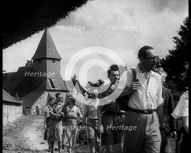 People Hiking with a Church in the Background, 1933. Creator: British Pathe Ltd.