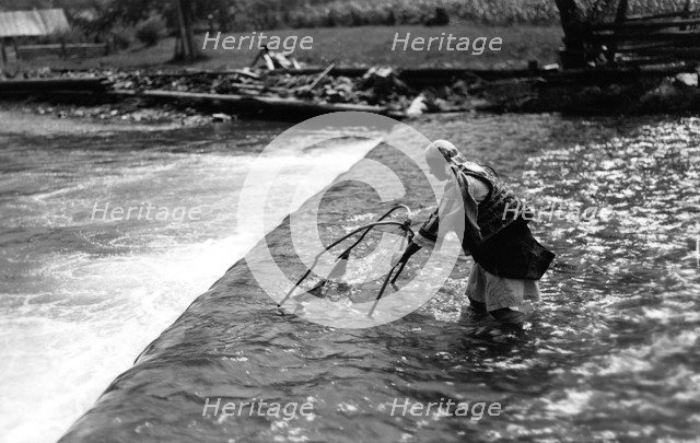 Woman fishing above a weir, Bistrita Valley, Moldavia, north-east Romania, c1920-c1945. Artist: Adolph Chevalier