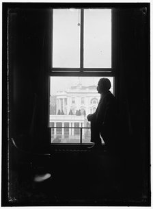 John Skelton Williams at window with White House visible in background..., between 1913 and 1918. Creator: Harris & Ewing.