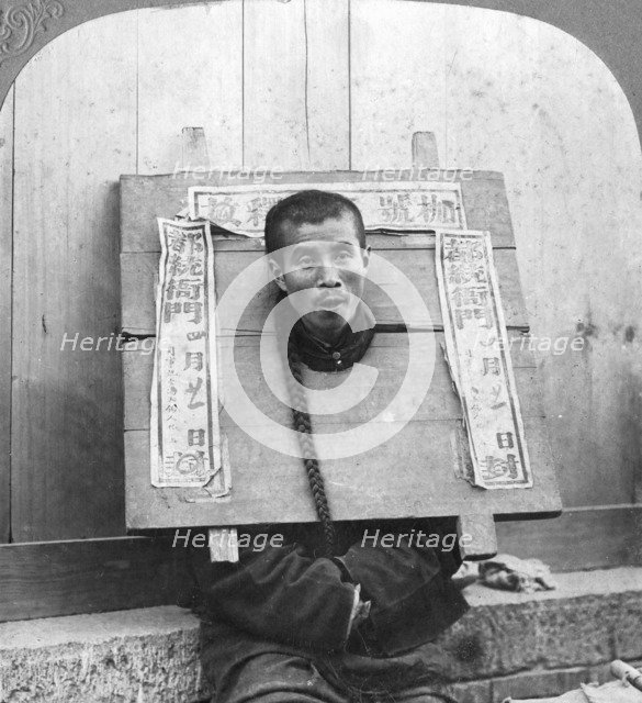 'Chinese prisoner in the cangue placarded with the record of his crime', China, 1902. Artist: CH Graves