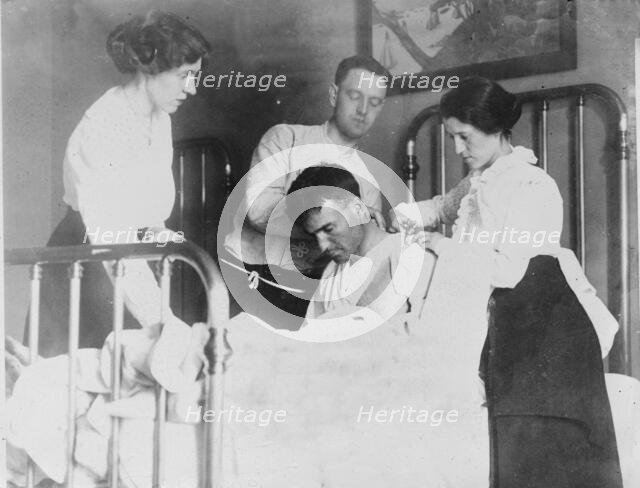 Dr. James F Grant, ship's surgeon, fixing up Gordan G Davidson, survivor of EMPRESS OF..., 1914. Creator: Bain News Service.