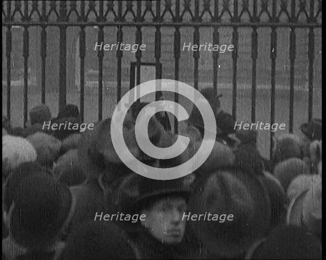 A Male Civilian Holding up a Bulletin from the Doctor to Crowds Gathering Outside..., 1929. Creator: British Pathe Ltd.