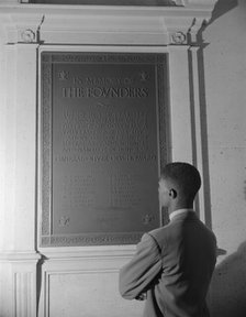 Student reading bronze plaque in library of Howard University, Washington, D.C., 1942. Creator: Gordon Parks.