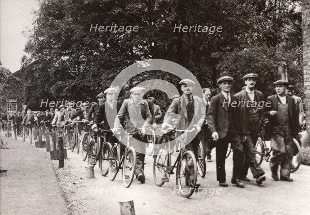 Men walk and wheel bicycles away from the Rowntree factory, York, Yorkshire, 1940. Artist: Unknown
