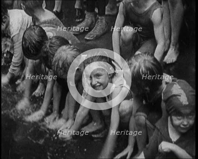Children Splashing in Water in the Gutter During a Heatwave in New York City, 1921. Creator: British Pathe Ltd.