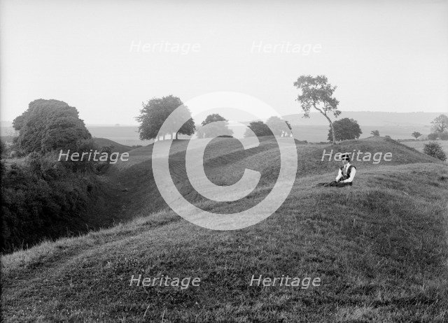 A woman sitting on the external bank at Avebury, Wiltshire, 1908. Artist: Harold St George Gray