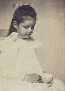 Young girl in white dress, seated holding teacup and saucer, c1900. Creator: Anne K Pilsbury.