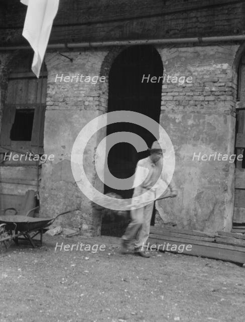 Man cleaning out a small building, New Orleans or Charleston, South Carolina, between 1920 and 1926. Creator: Arnold Genthe.