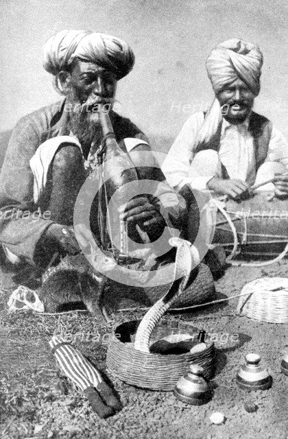 Charming the venom from a cobra; a snake charmer with a mongoose, India, 1922.Artist: JH Powell