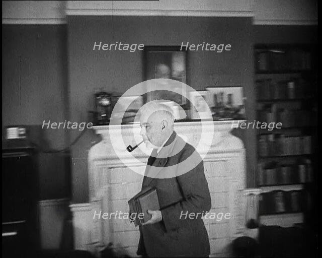 C.E.M Joad Taking Some Books to His Desk, 1930s. Creator: British Pathe Ltd.