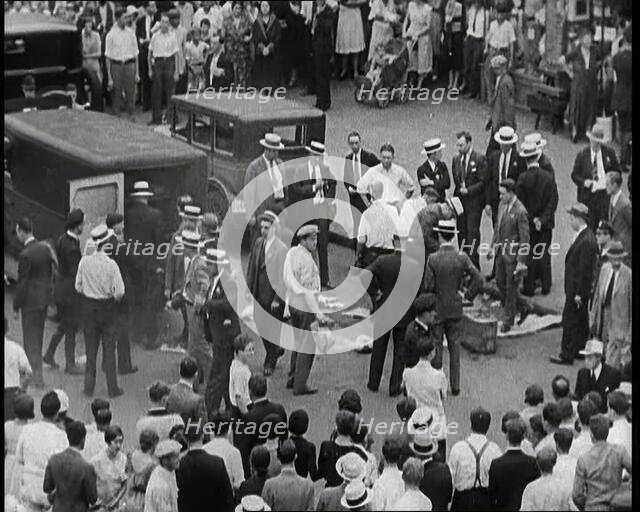 Crowded New York City Street Where Police and Ambulance Attend to Dead and Dying Victims..., 1932. Creator: British Pathe Ltd.