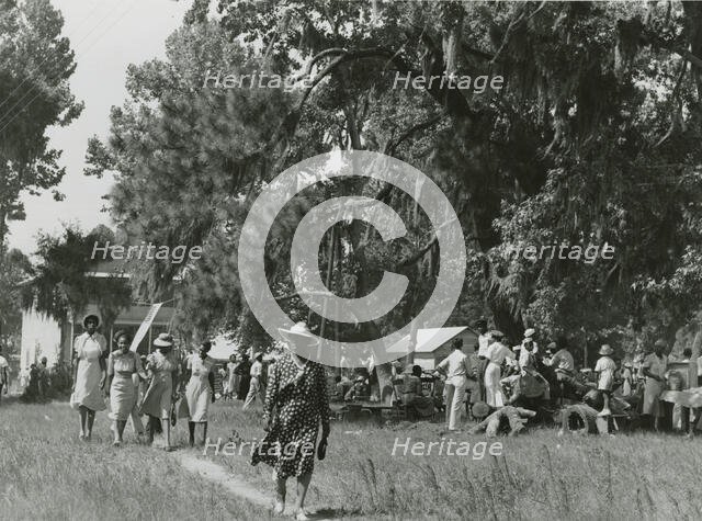 African Americans walking in an open field at a picnic, Beaufort, South Carolina, July 4, 1939. Creators: Farm Security Administration, Marion Post Wolcott.