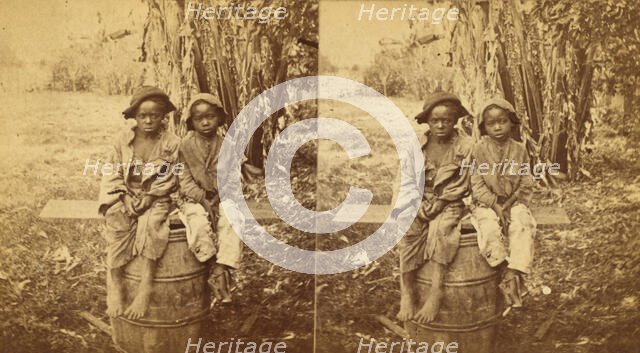 Happy little nig's, [Two boys sitting on a barrel in a field], (1868-1900?). Creator: Unknown.