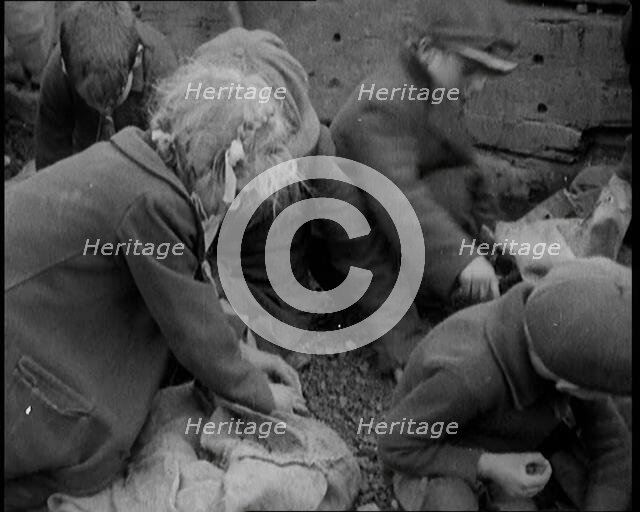 Close up of Male and Female Children Picking Through Small Heaps of Coal on the Ground, 1924. Creator: British Pathe Ltd.