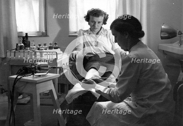 A Rowntree’s chiropodist works on a woman’s foot, York, Yorkshire, 1946. Artist: Unknown