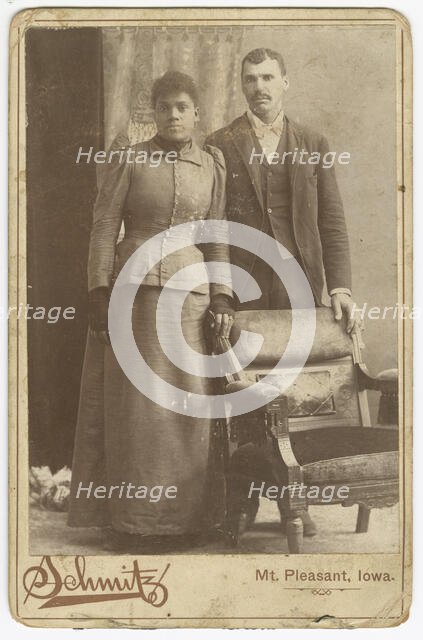 Photograph of an African-American couple standing behind a chair, ca. 1890. Creator: Schmitz Studio.