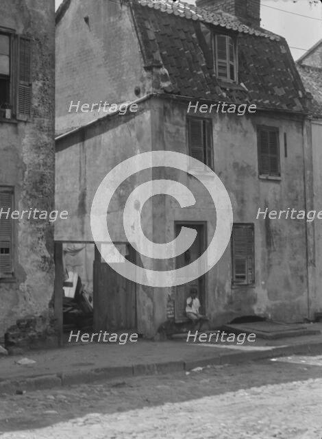Boy sitting in the doorway of a two-story building, [17 Chalmers Street], Charleston..., c1920-c1926 Creator: Arnold Genthe.
