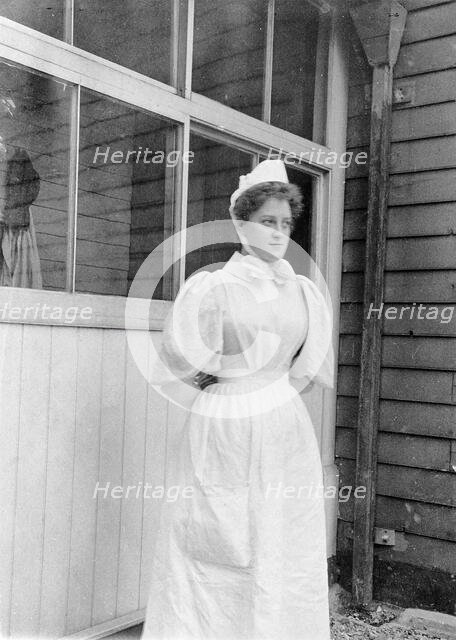 Nurse standing outside an isolation hospital, possibly at Ilford, Essex. Creator: Unknown.