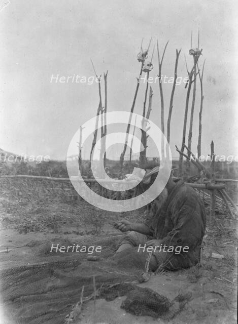 Ainu seated outside working on nets, 1908. Creator: Arnold Genthe.