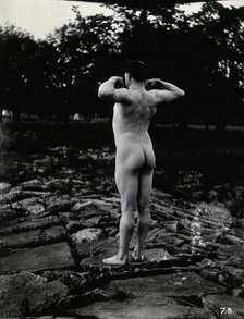 A man posing naked, with his back to the camera, standing on a rocky outcrop, c1900. Creator: Unknown.