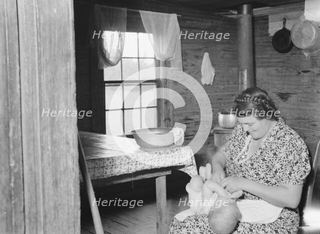 Wife of tobacco sharecropper bathing baby in kitchen, Person County, North Carolina, 1939. Creator: Dorothea Lange.