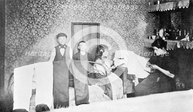 Domestic scene showing a mother with her children finishing trousers, London, c1900. Artist: Unknown