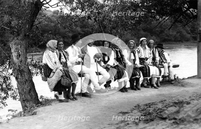 Group of people seated on a bench, Bistrita Valley, Moldavia, north-east Romania, c1920-c1945. Artist: Adolph Chevalier