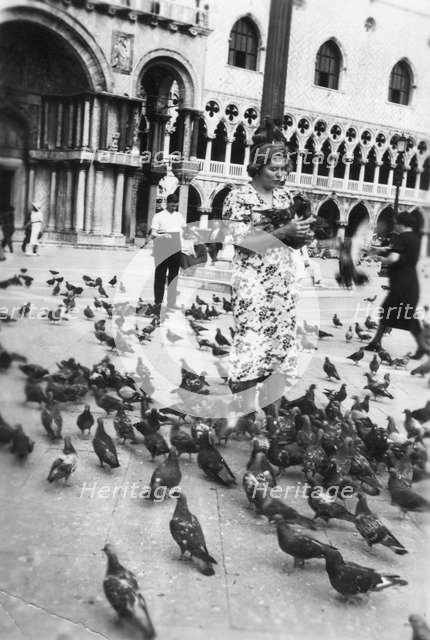 Woman surrounded by pigeons, St Mark's Square, Venice, Italy, 1938. Artist: Unknown