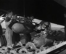 RAF Ground Crew Members Fixing Bombs to an Avro Lancaster Bomber, 1942. Creator: British Pathe Ltd.