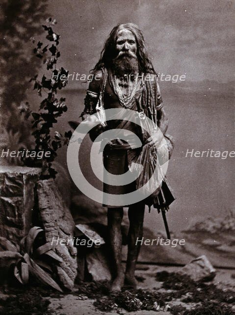 An Indian man wearing many beads, and carrying a begging bowl and an umbrella, in a..., c1900. Creator: Unknown.