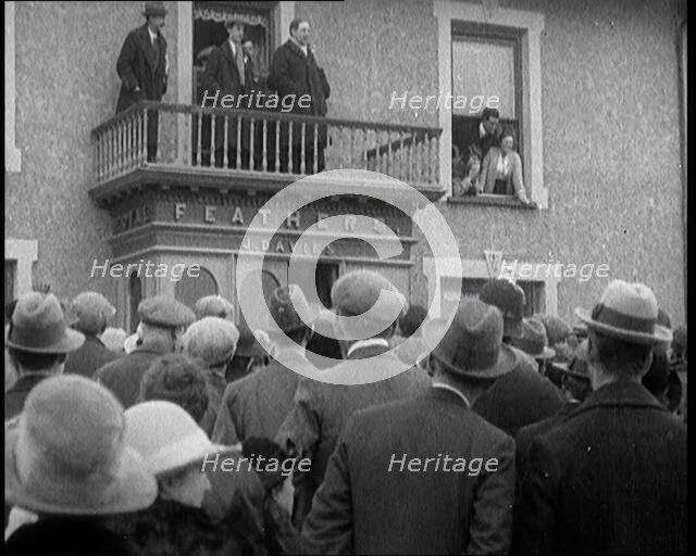 British Man Speaking to a Crowd from the Balcony of a Building Marked 'Feathers J. Davies..., 1921. Creator: British Pathe Ltd.